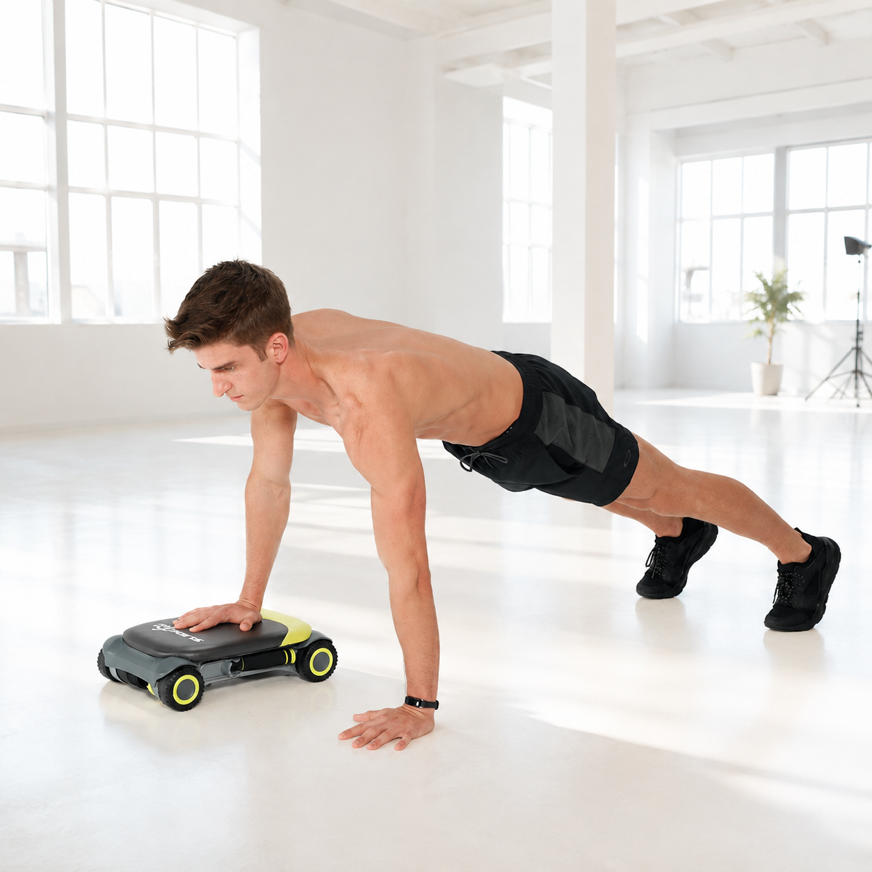 Man in a plank position bracing one hand on a Wonder Core Slide Fit board in a bright studio, using it as a core platform rather than a basic ab-roller roll-out