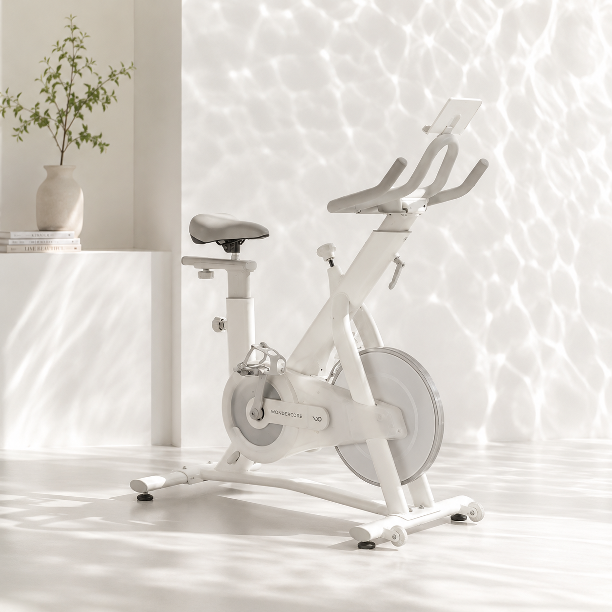 White Wondercise smart spin bike with tablet holder in a bright minimalist room, ready for FTMS Bluetooth pairing with Zwift