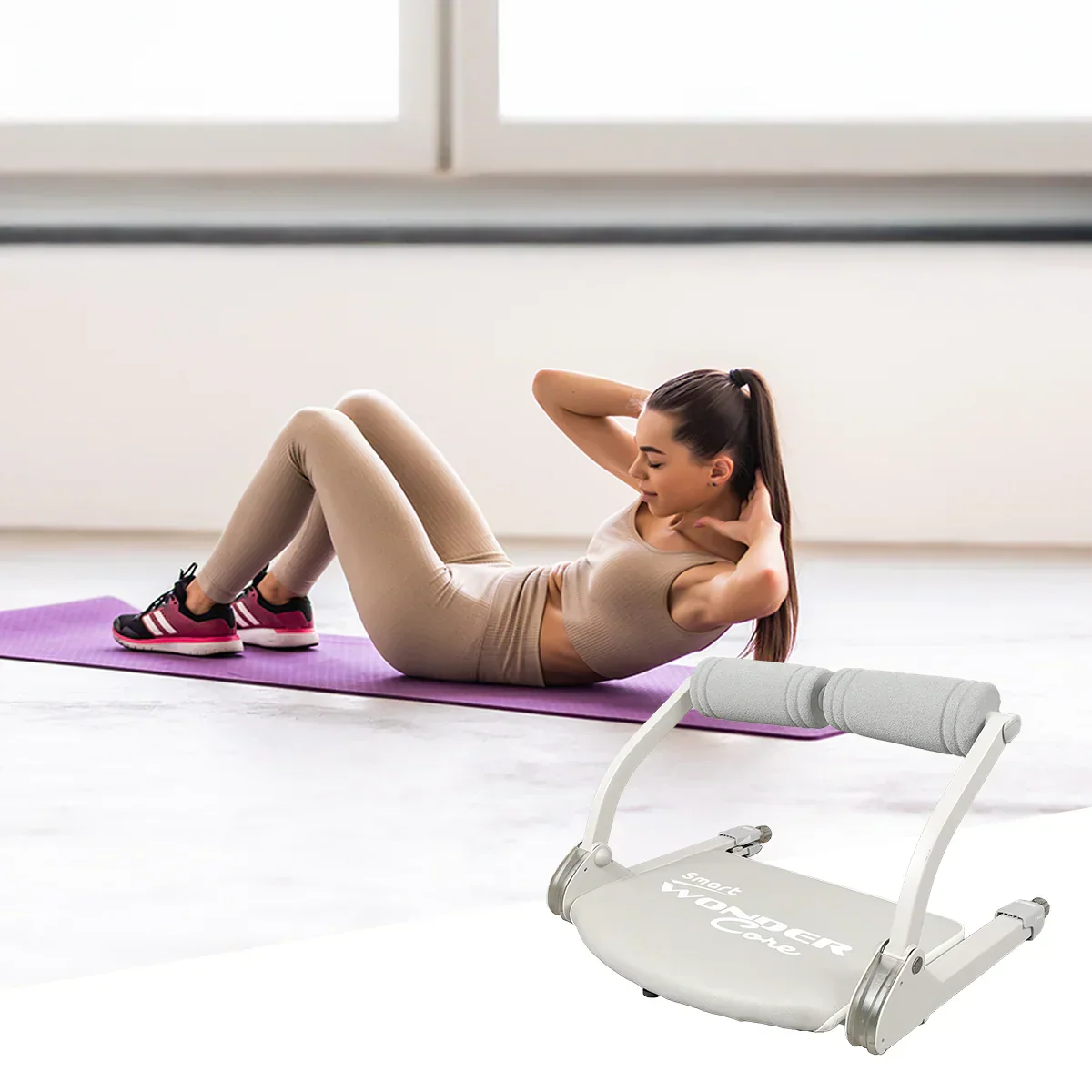 Woman doing a crunch on a purple yoga mat beside a white Wonder Core Smart ab trainer in a bright room, an at-home belly-fat workout